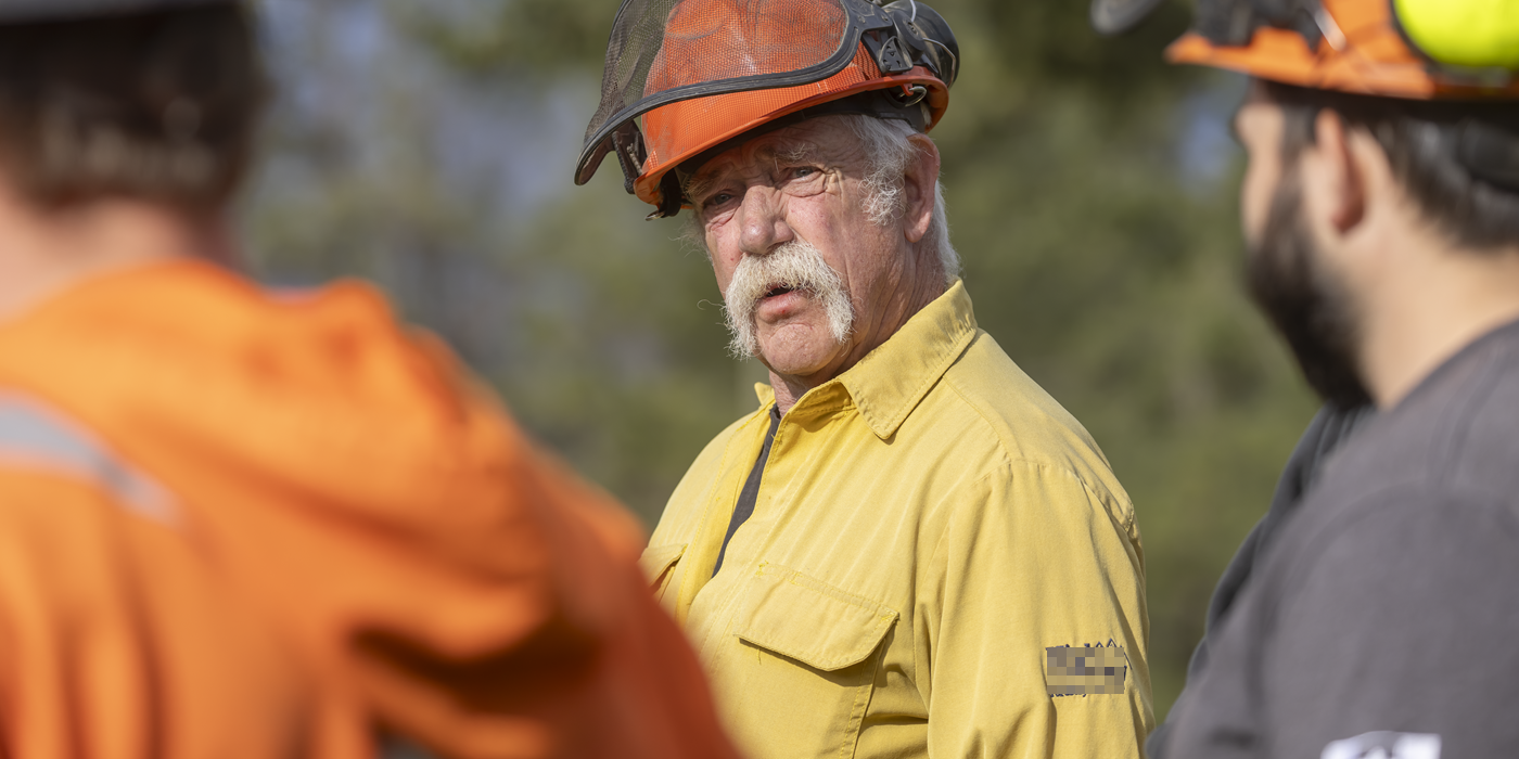 Three firefighters in hardhats talking outdoors