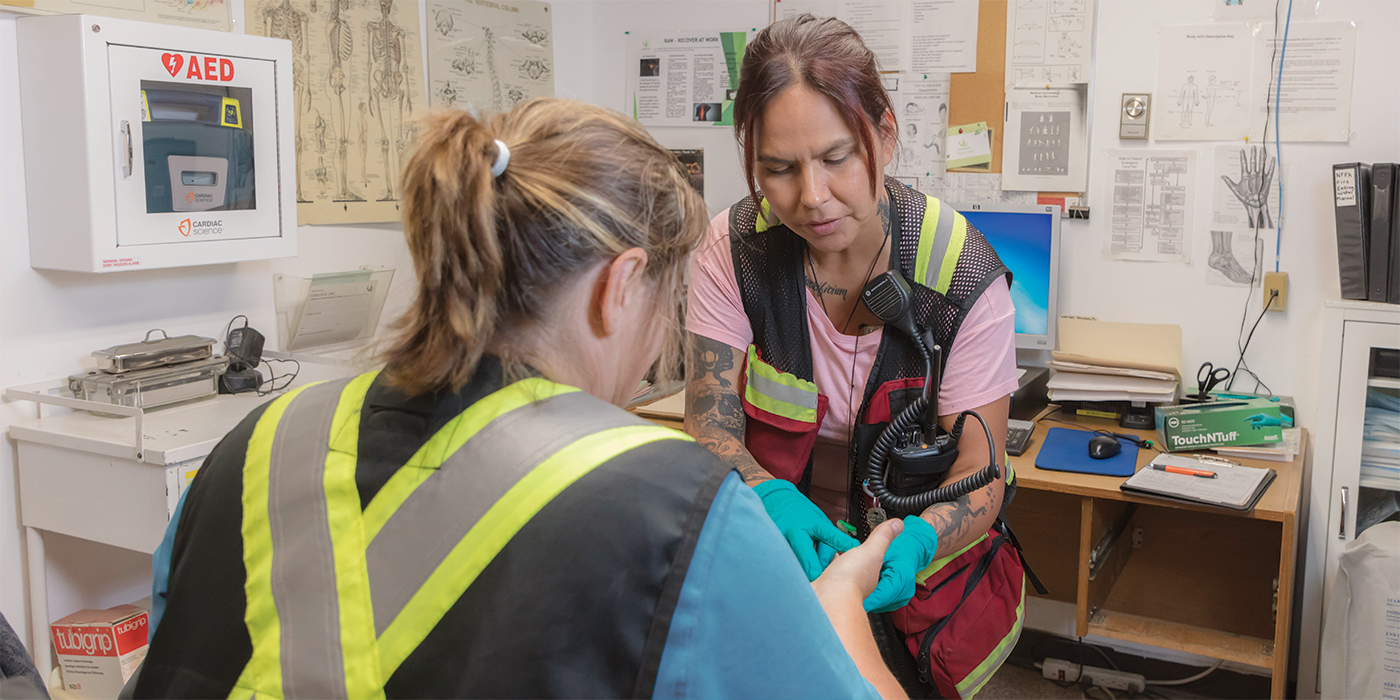 Photo of first aid attendant administering treating a worker's hand injury